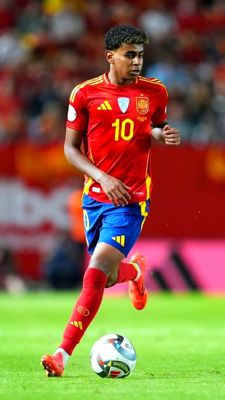 A soccer player in a red and yellow Spain jersey with the number 10 is running with the ball during a match, as blurred spectators look on—perfect action to catch live on Romania IPTV.